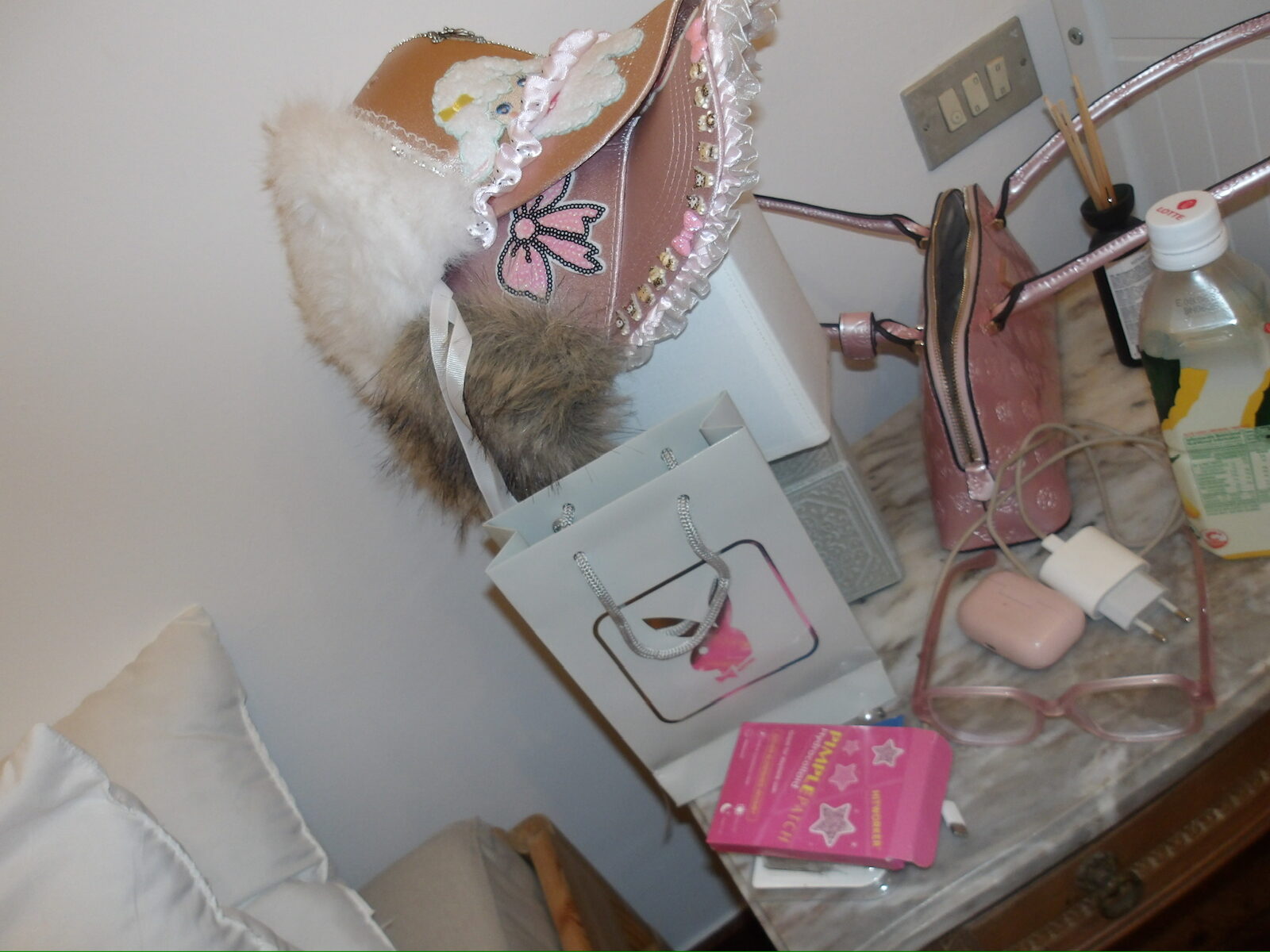 Bolsos, gorro de peluche y accesorios rosas sobre una mesa
