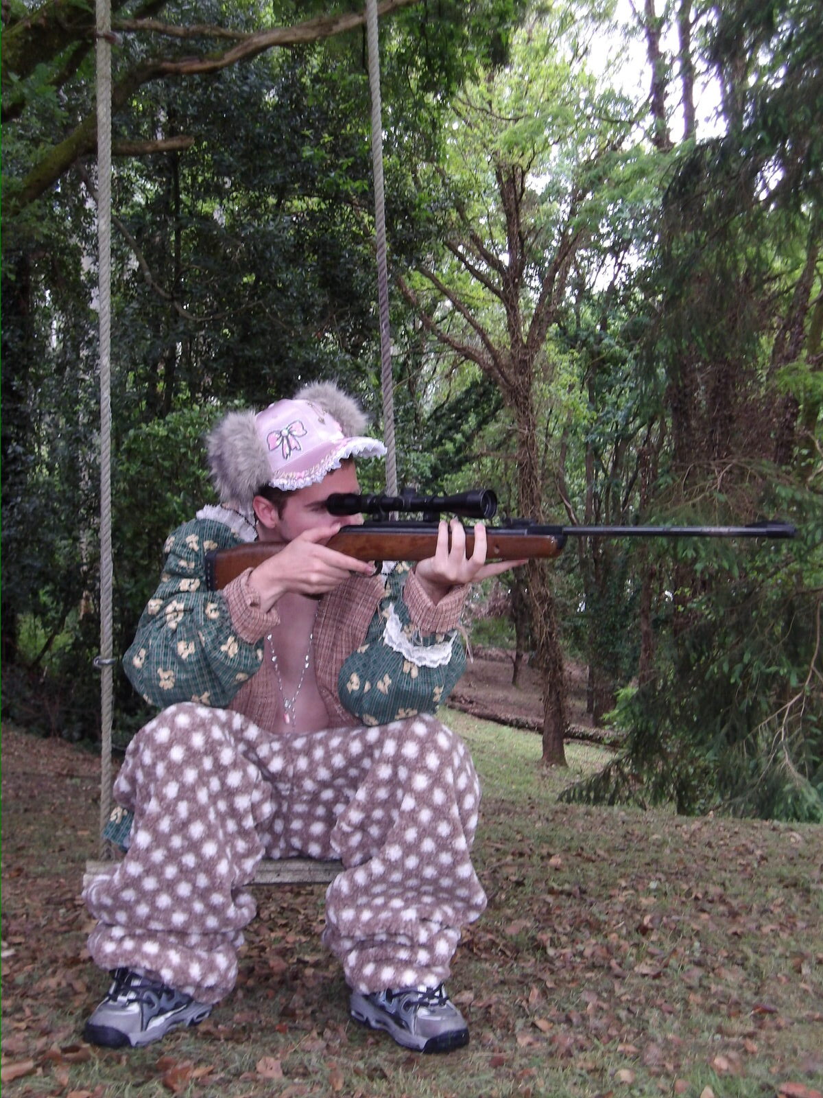 Modelo con rifle y pantalón de lunares en el bosque